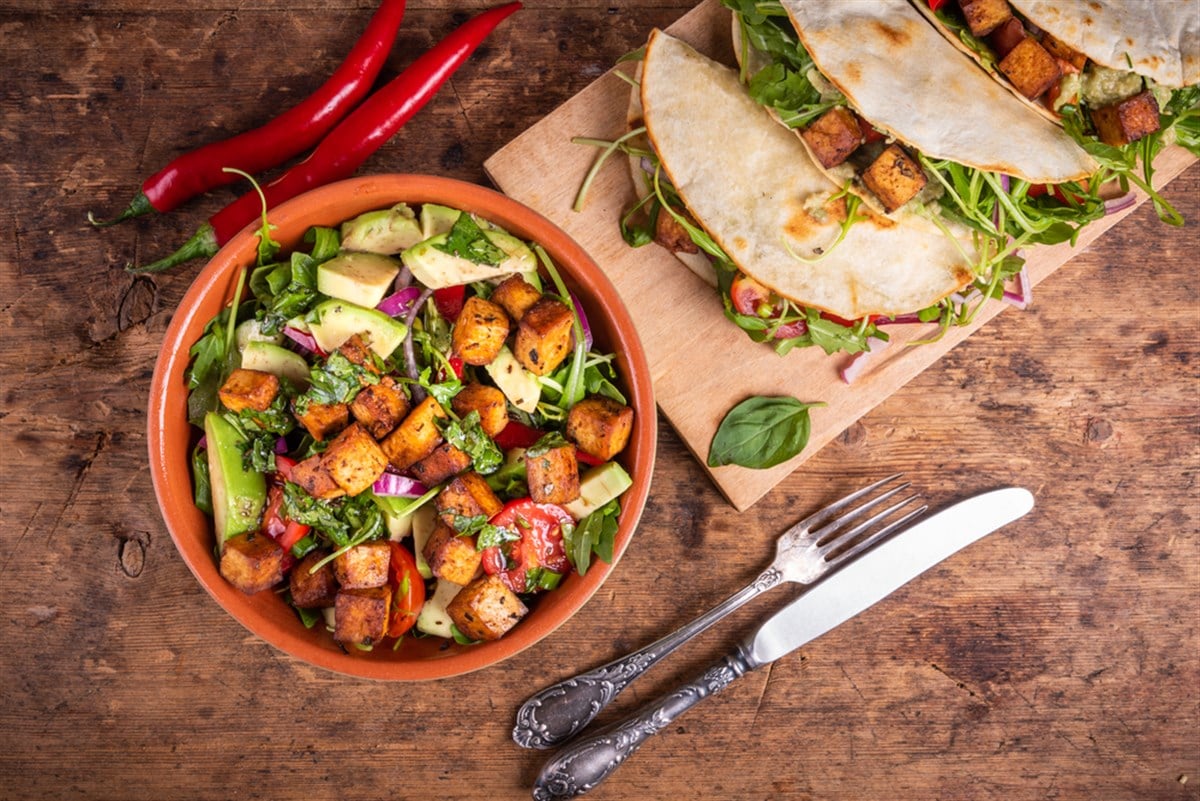Vegetable salad with fried tofu in a bowl and vegan tacos with waxes, tofu and hot peppers, top view - vegetarian cuisine