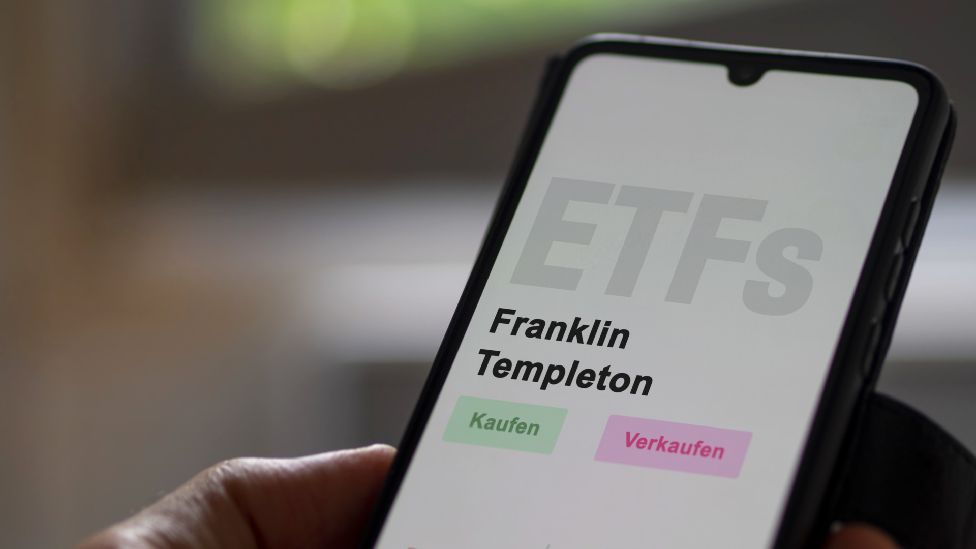 An investor's analyzing the Franklin Templeton etf fund on screen. A phone shows the ETF's prices Franklin Templeton to invest. German text.