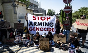 A group of Israeli and international activists gather in front of the British consulate in Jerusalem, protesting aganst the UK's arms exports to Israel and holding a banner that reads 'Stop arming genocide'