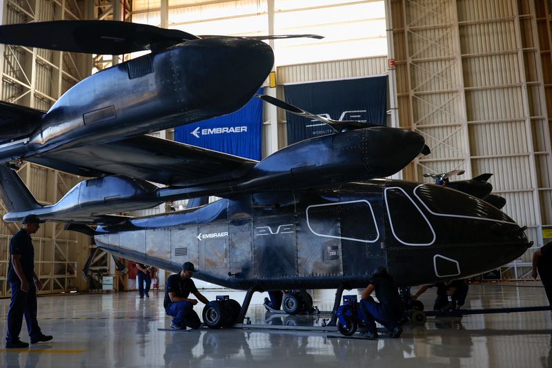 © Reuters. FILE PHOTO: Employees work near the full-scale prototype of an electric vertical take-off and landing (eVTOL) aircraft developed by Eve Air Mobility, an Embraer group company, as it is presented for the first time in Gaviao Peixoto, Brazil July 3, 2024. REUTERS/Amanda Perobelli/File Photo