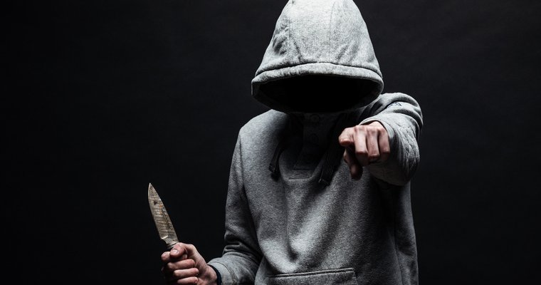 hooded man carrying a knife