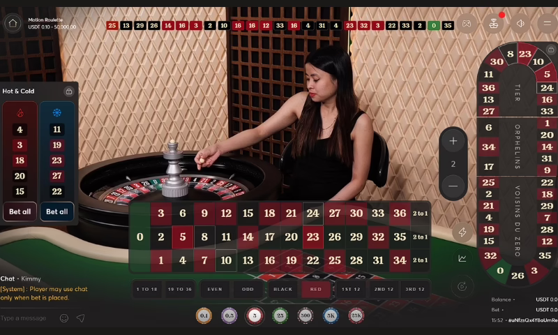 A live professional dealer on the roulette wheel with the gaming interface on the screen. 