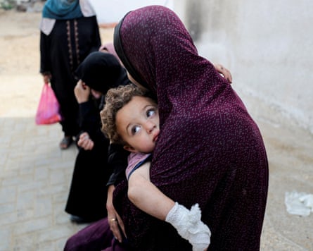 A mourner holds a child as she attends the funeral of Palestinians killed in Israeli strikes