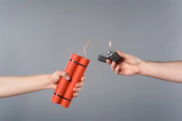 Cropped view of men holding dynamite and lighter on grey background