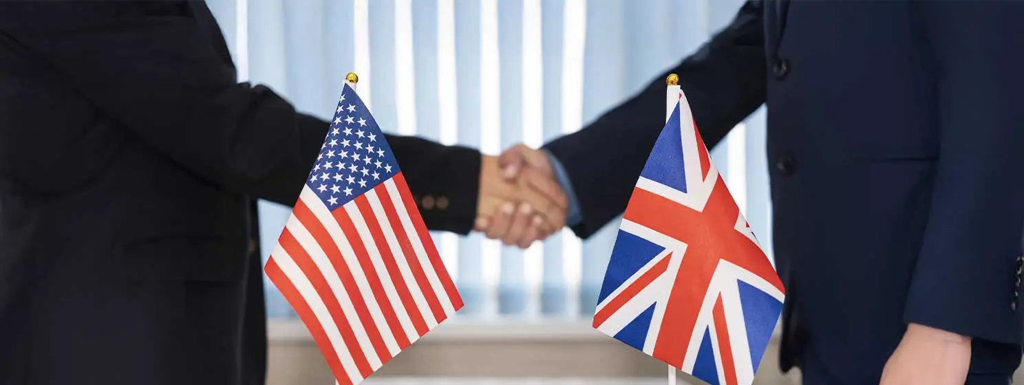 Two men handshakes with US and UK political flags in the middle