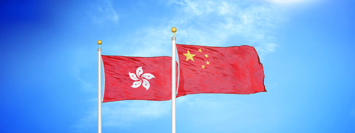 Hong Kong and China two flags on flagpoles and blue cloudy sky background.