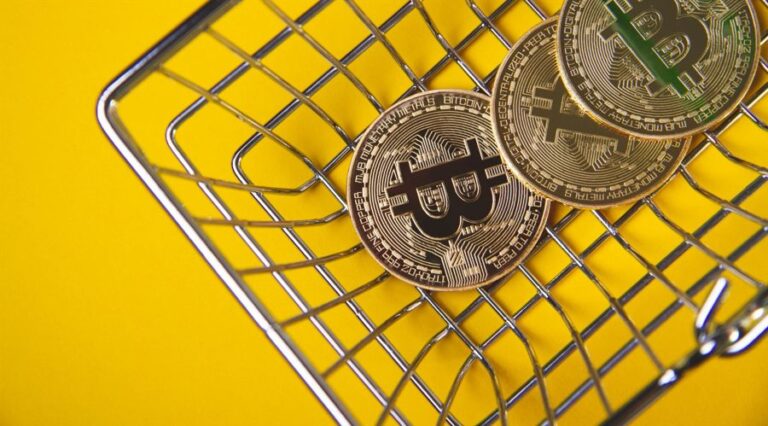 bitcoin tokens laying in the shopping cart, yellow background