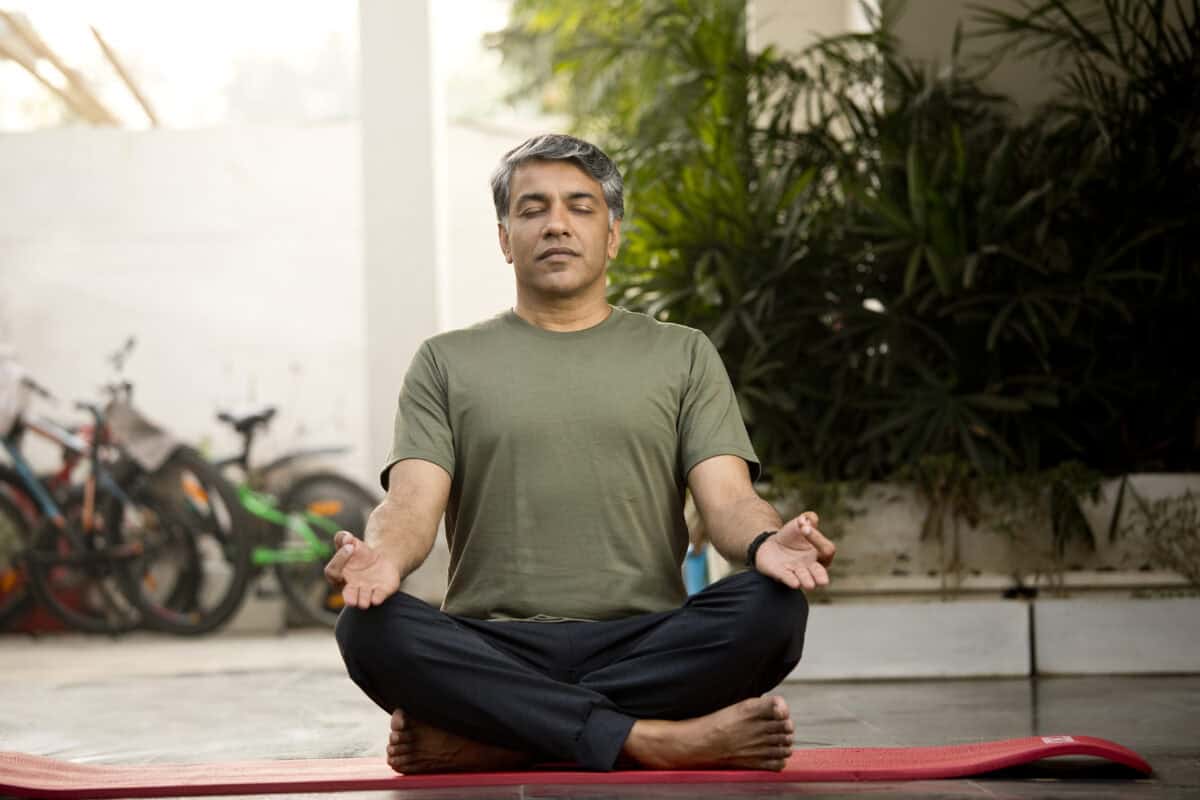 Man meditating in lotus position outdoor on patio