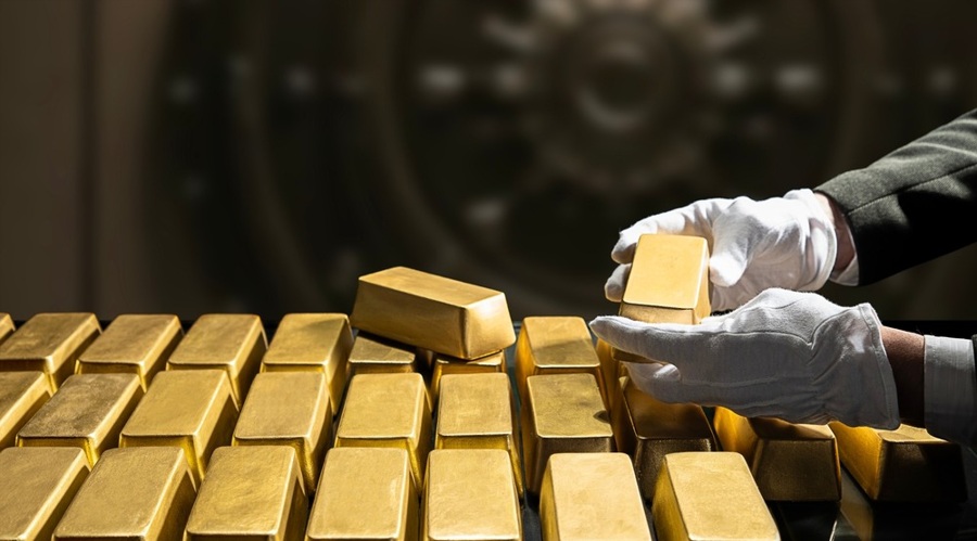 A banker’s hands in white gloves holding a gold bar, symbolizing national gold reserves.
