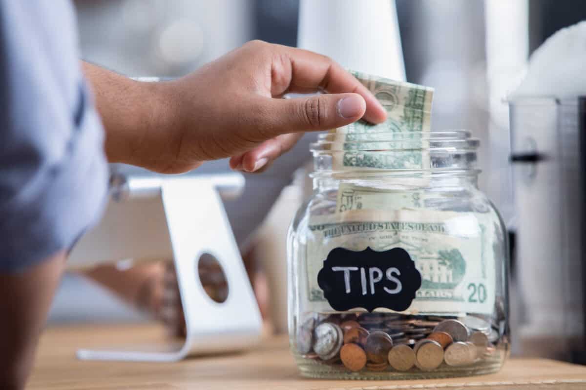 customer adds cash to tip jar at business