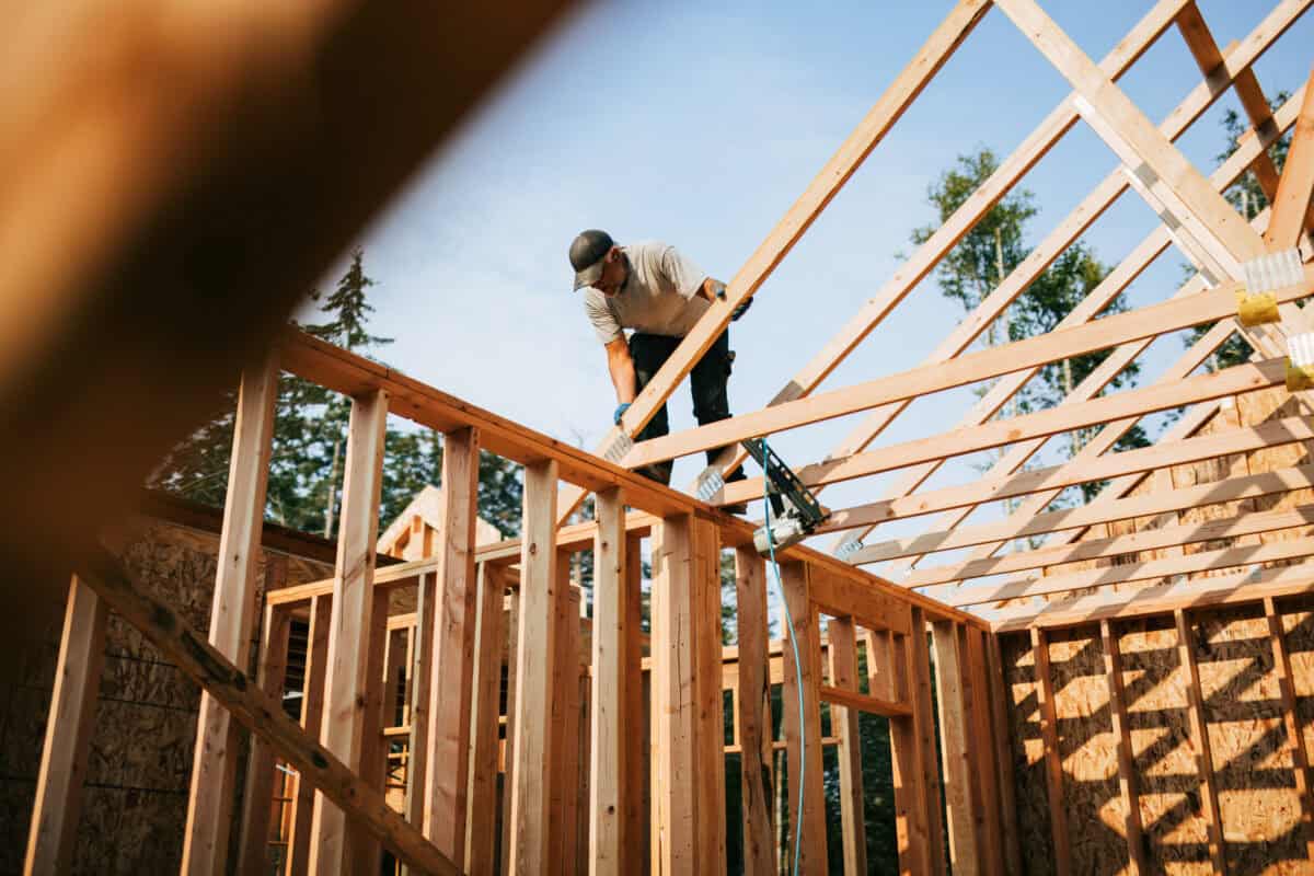 builder frames a house with lumber