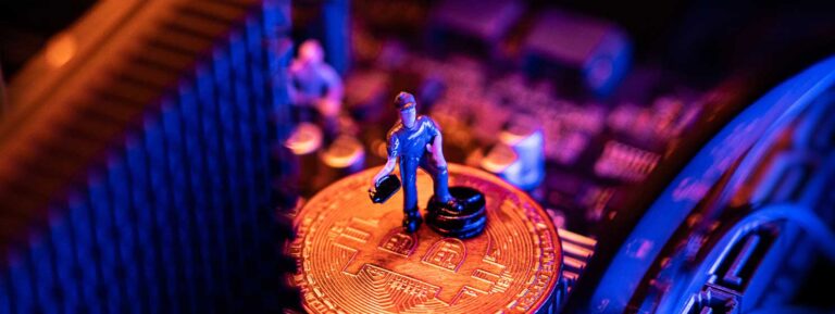 Toy miner on a Bitcoin coin atop a computer motherboard